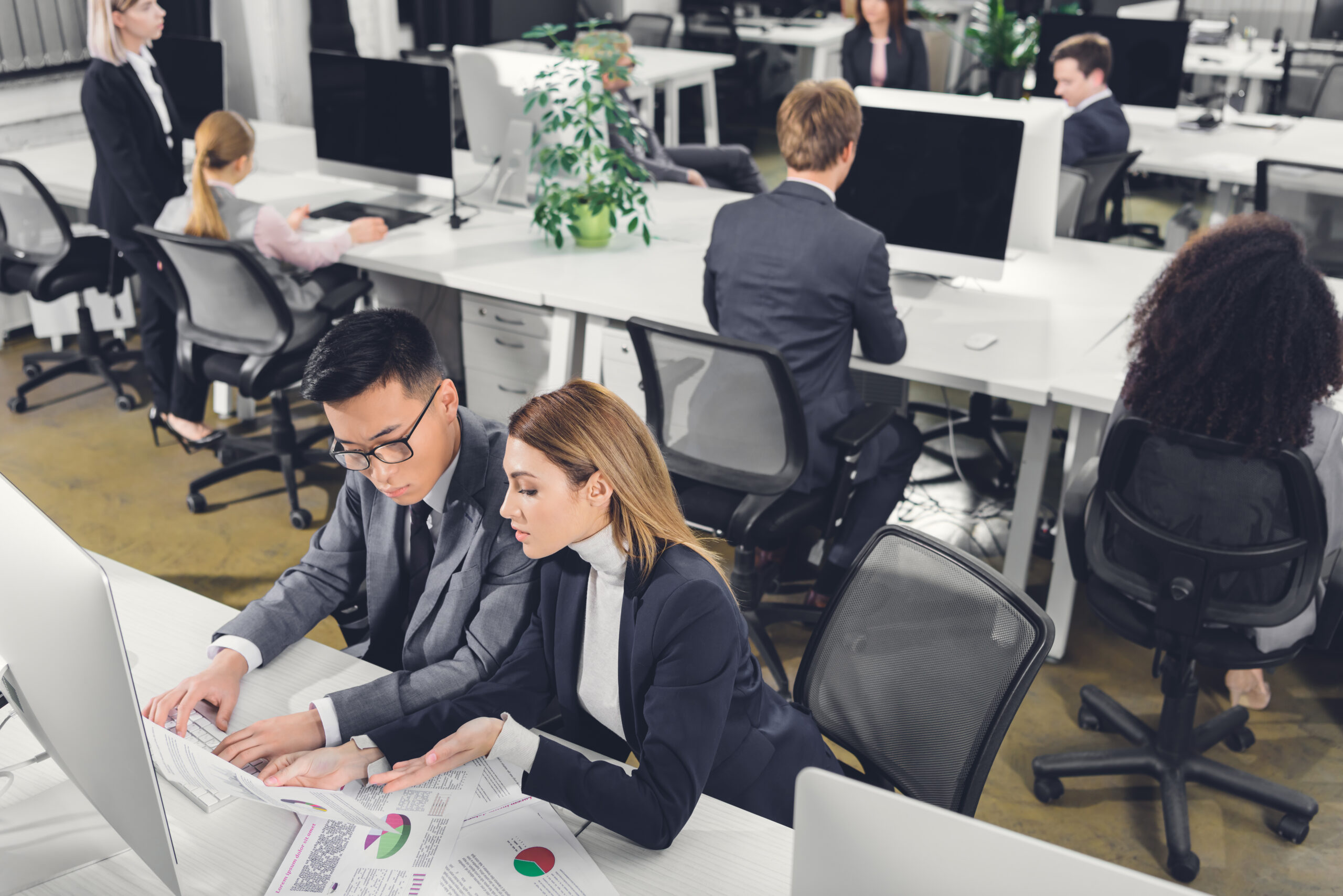 high angle view of young businessman and businesswoman using desktop computer and working with