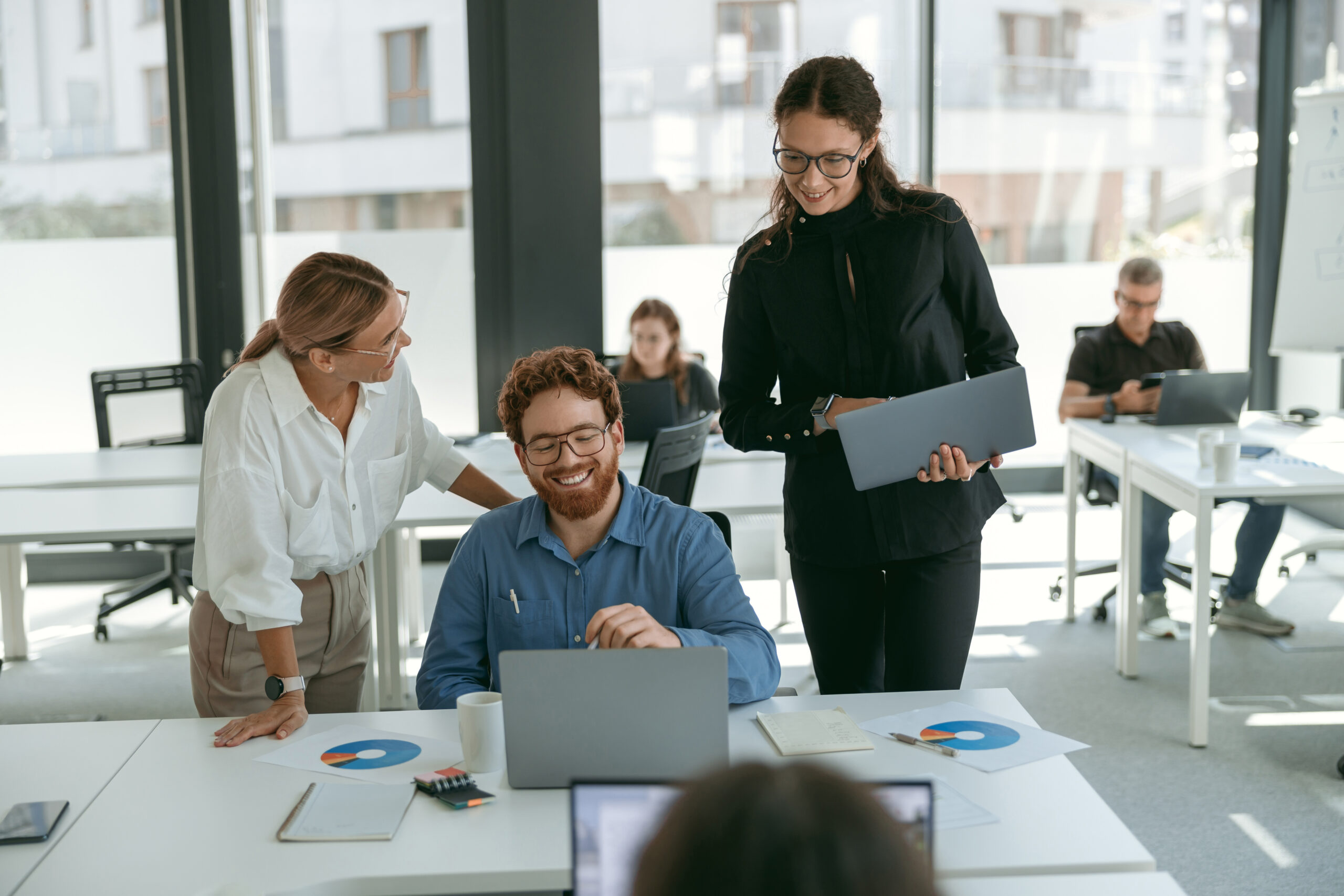 Group of young business people discussing something and smiling while sitting at the office table